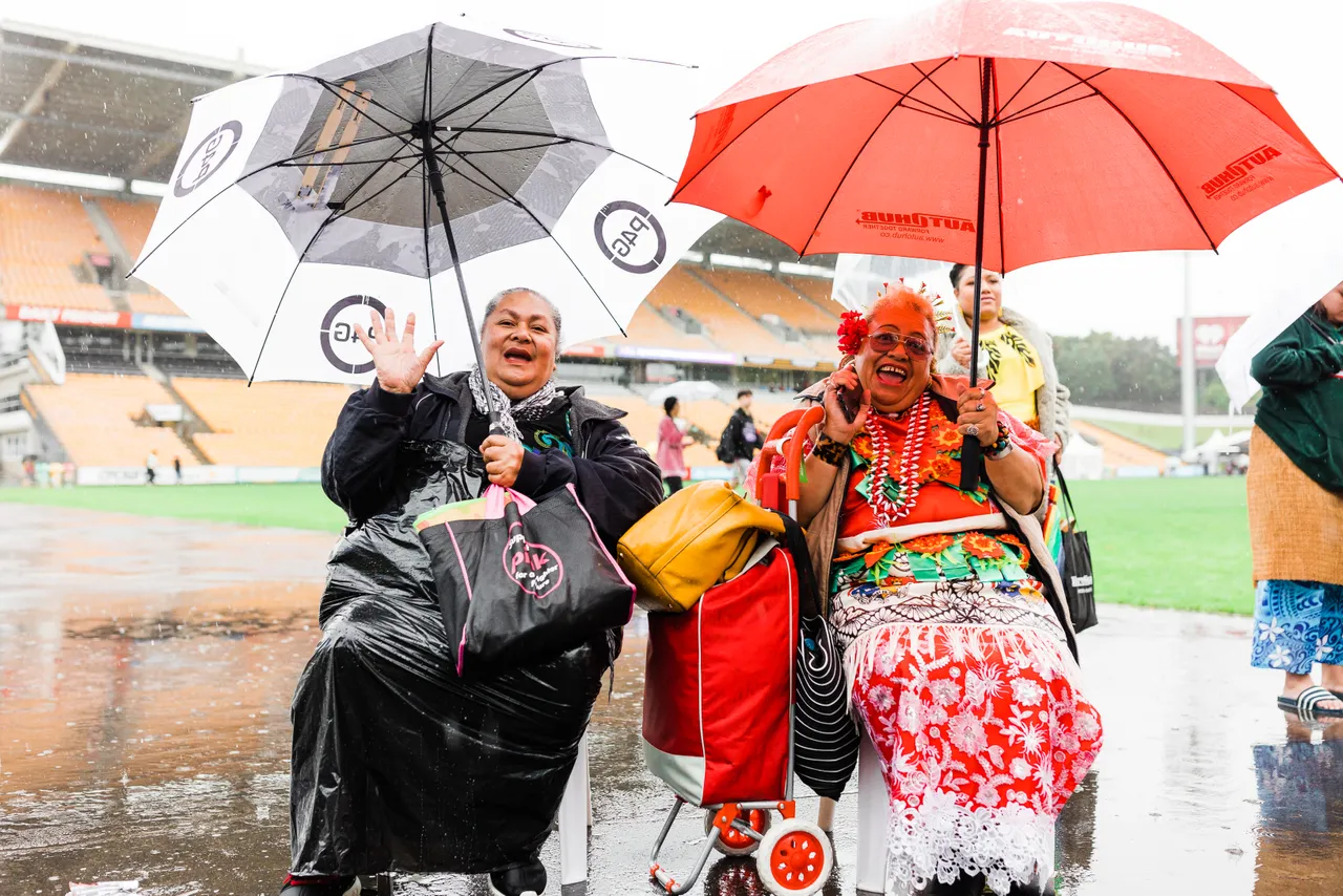 Two women under umbrellas singing in the rain